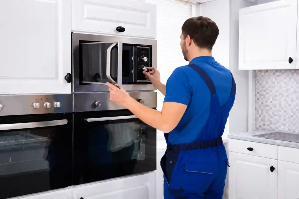 Technician servicing a built-in microwave in a modern kitchen.