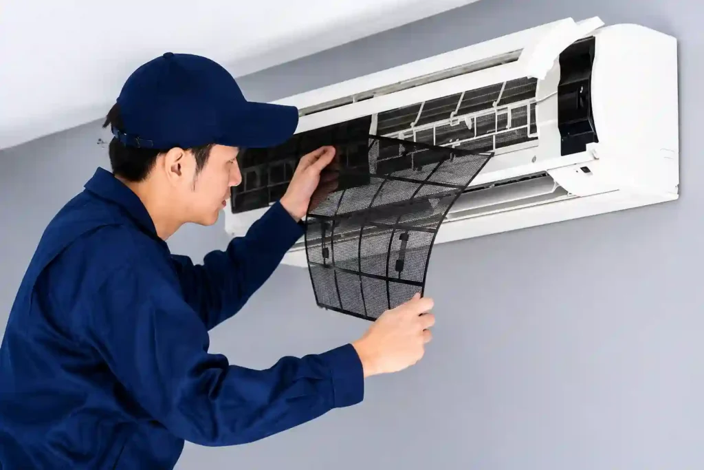 Technician removing and cleaning the filter of a wall-mounted split AC.